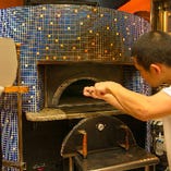 ナポリの本格ピッツェリアを彷彿させる青いタイルが印象的な石窯。400度の石窯で一気に焼き上げるピッツァは、サクッと香ばしくて美味。