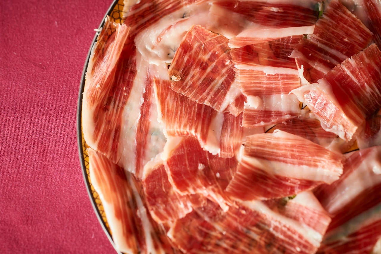 お皿に敷き詰められた、きれいな赤色のハモン・イベリコ・デ・ベジョータ 