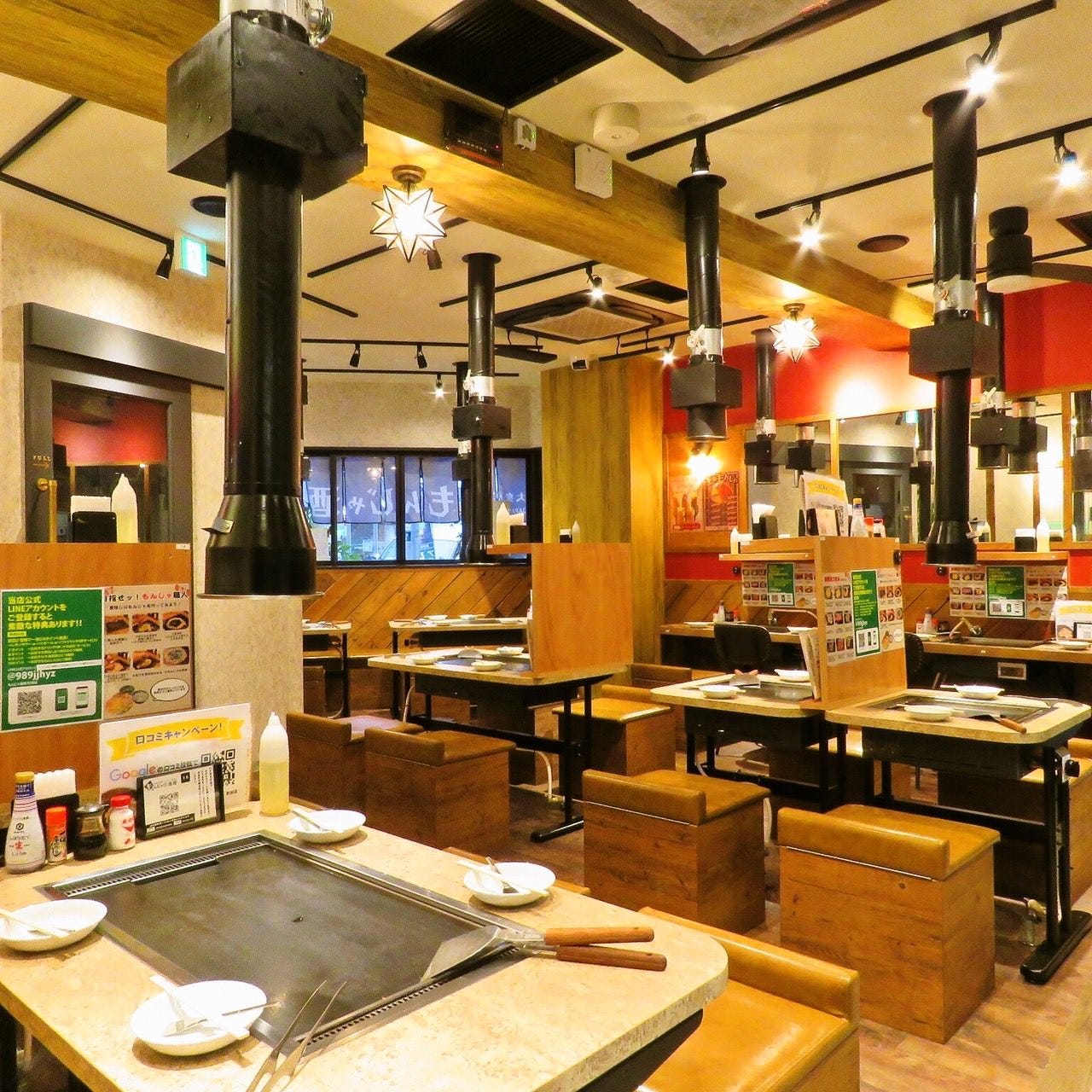 鉄板がついたテーブルが並べられた大衆居酒屋 もんじゃ酒場 だしや町田店の店内