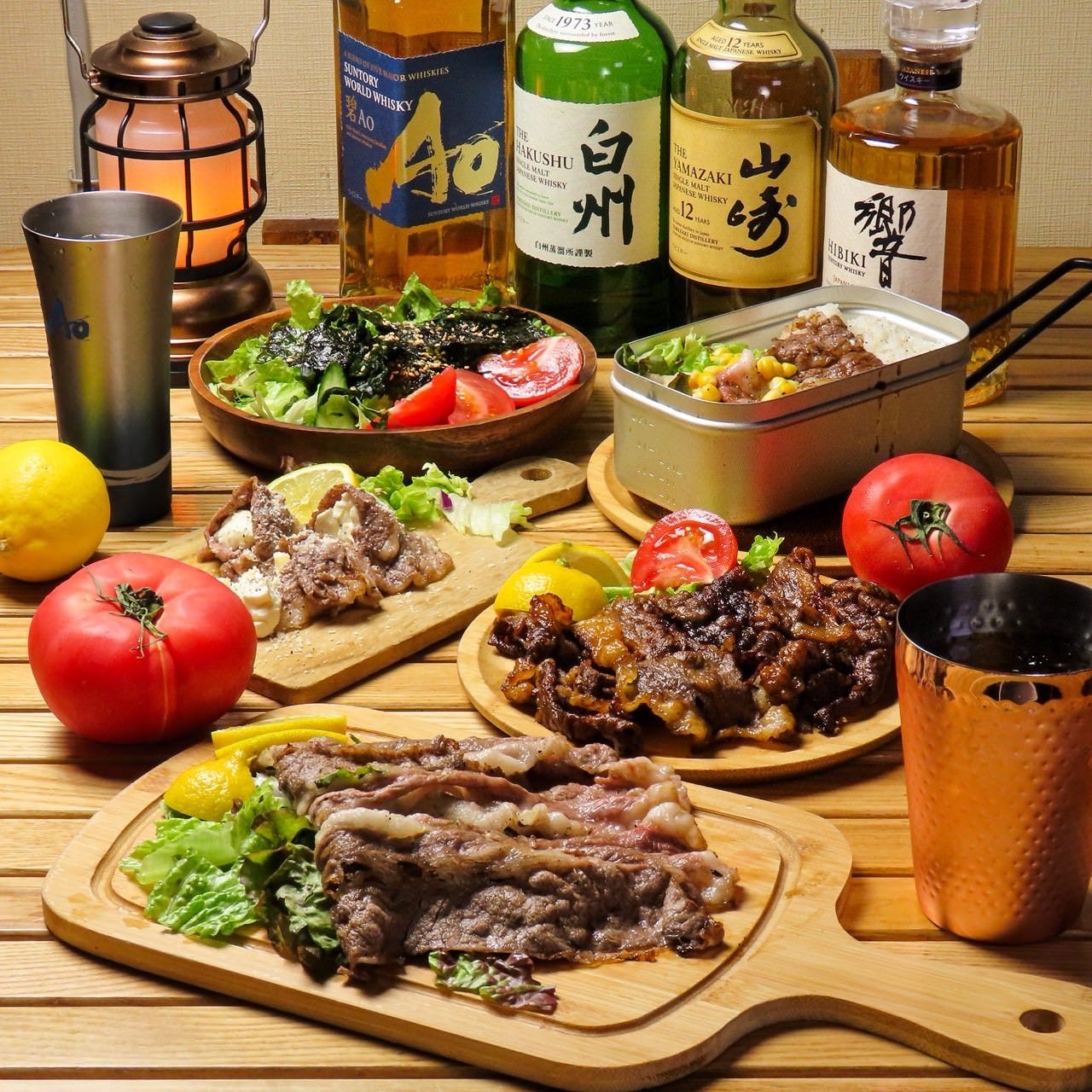 木のボードにのった肉や野菜とお酒のボトル、グラス