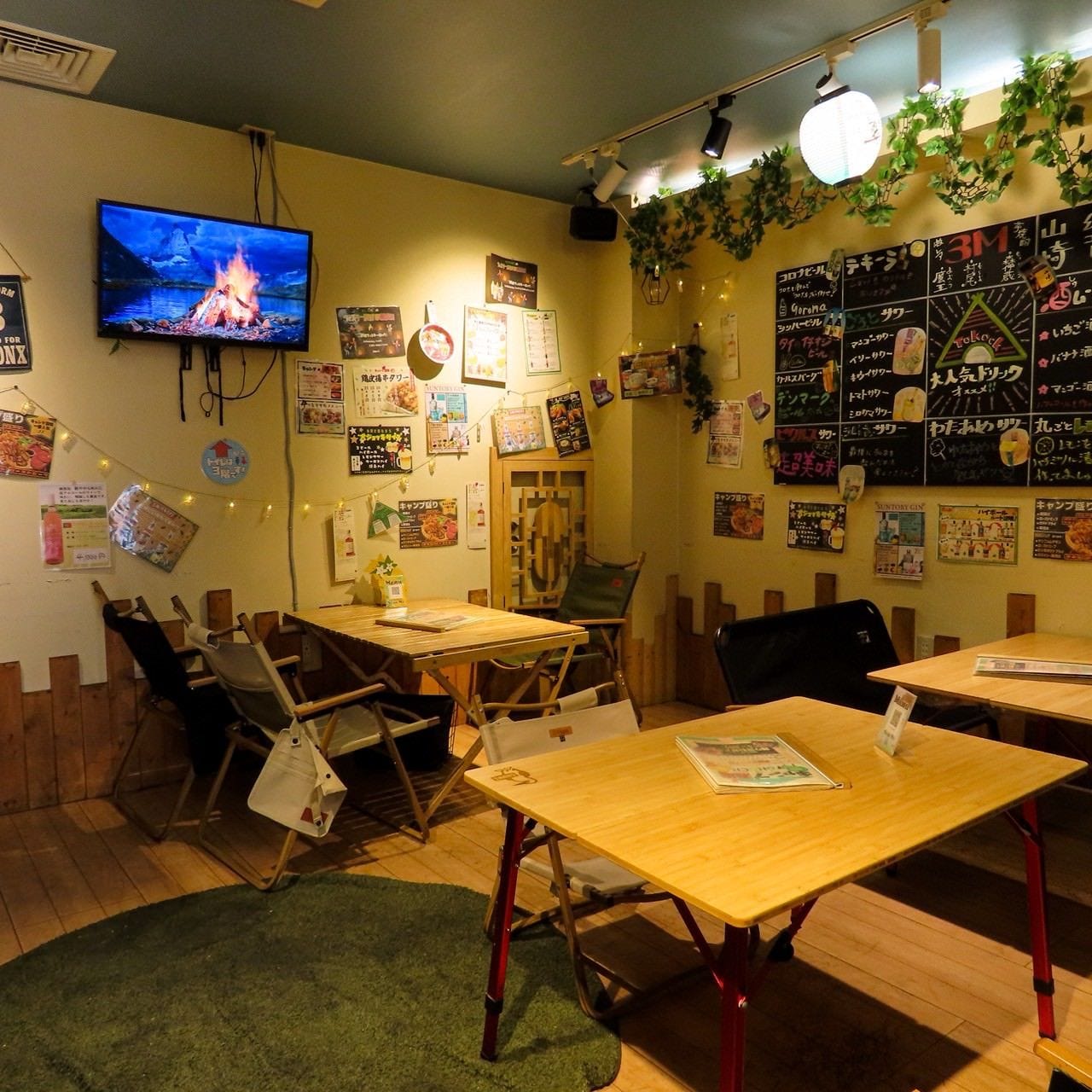 キャンプチェアやテーブルが置かれ、黒板や写真が飾られているキャンプ酒場 トックオックの店内